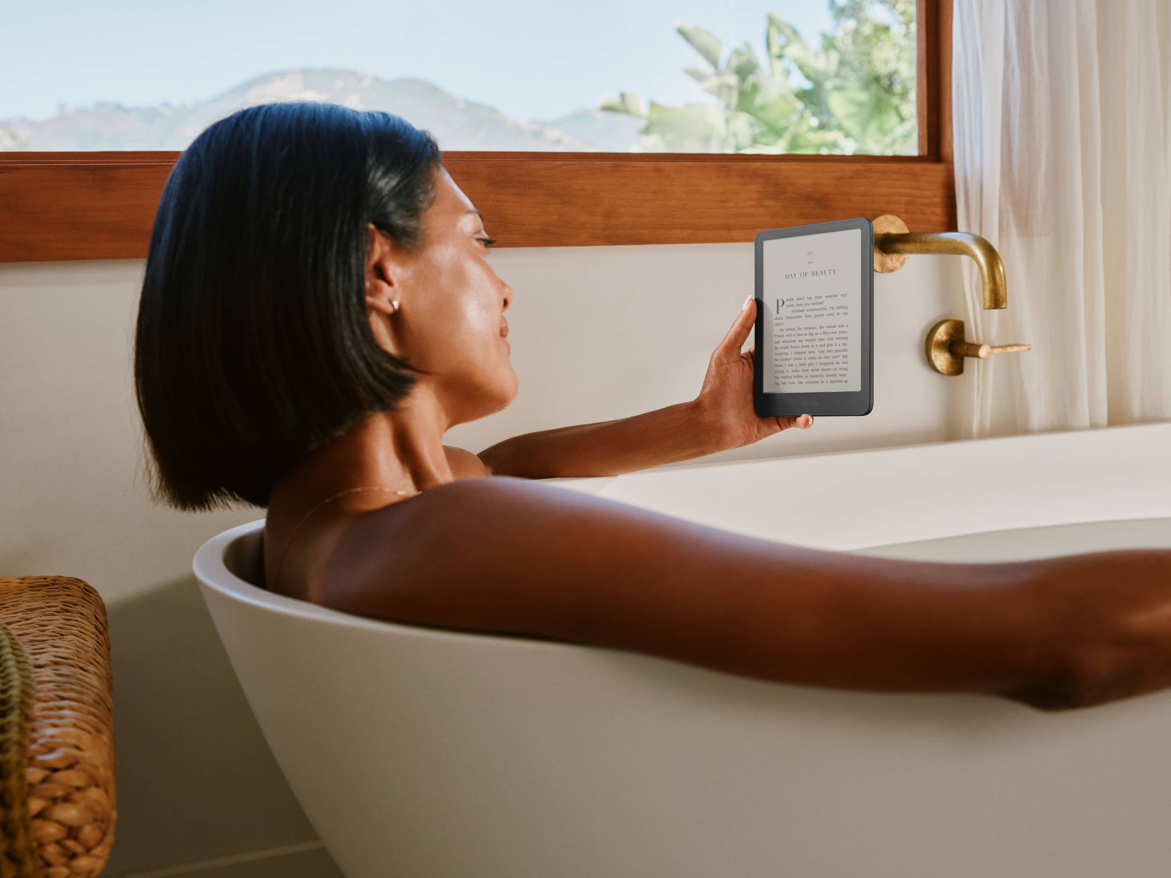 Person relaxing in bathtub reading Amazon Kindle Paperwhite.