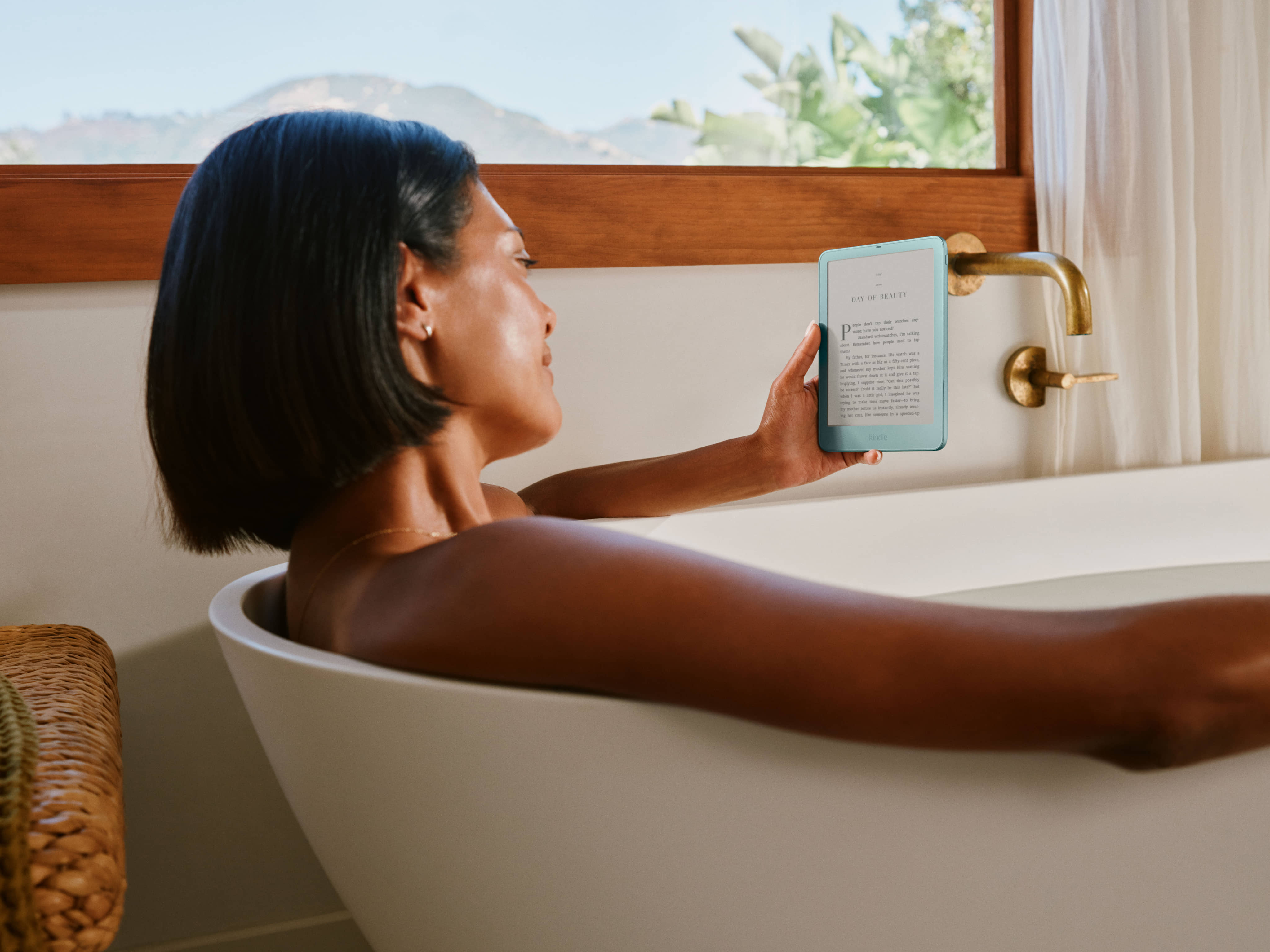 Person reading Amazon Kindle e-reader in bathtub.