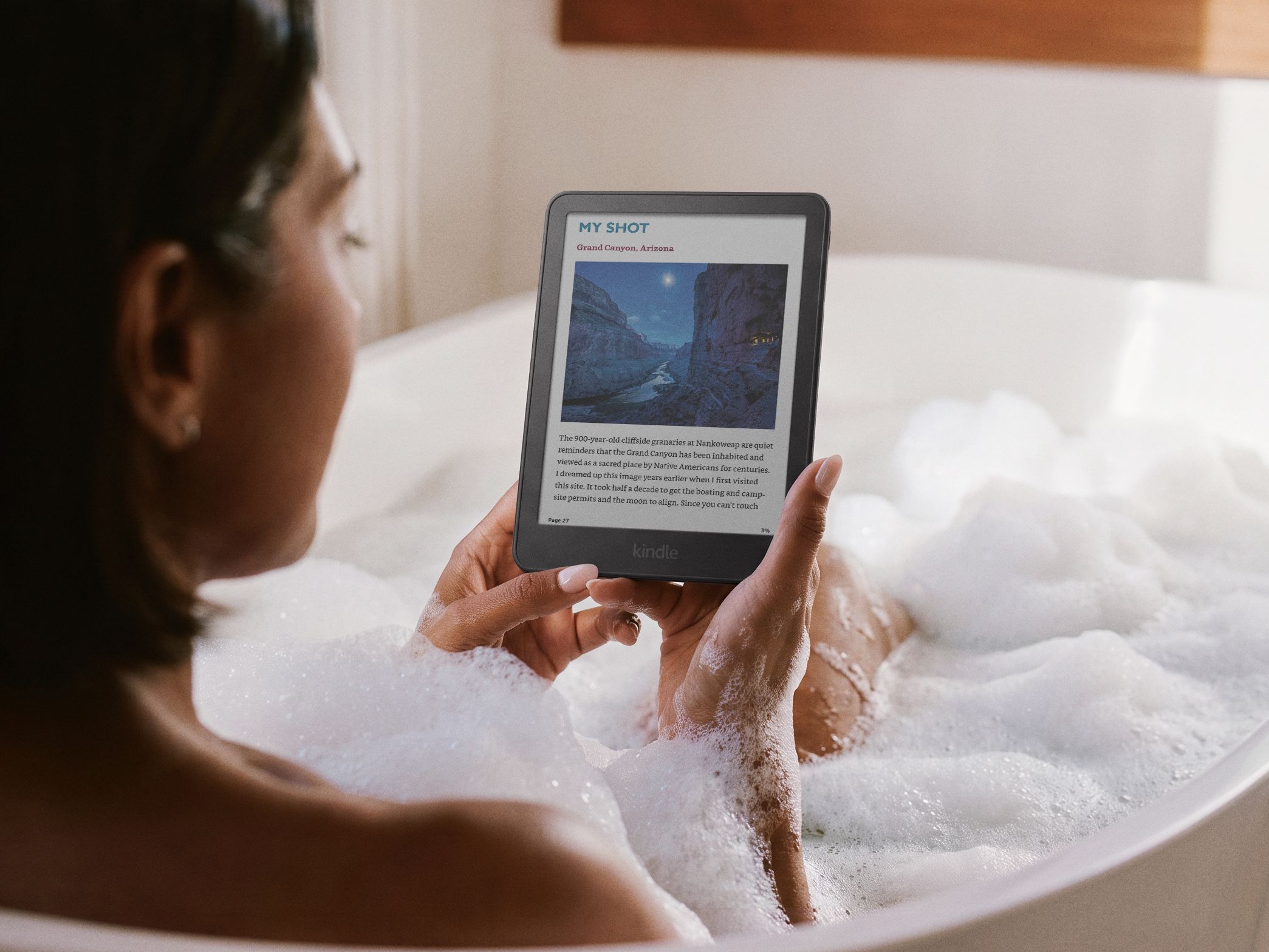 Person reading on Amazon Kindle e-reader while relaxing in bathtub.