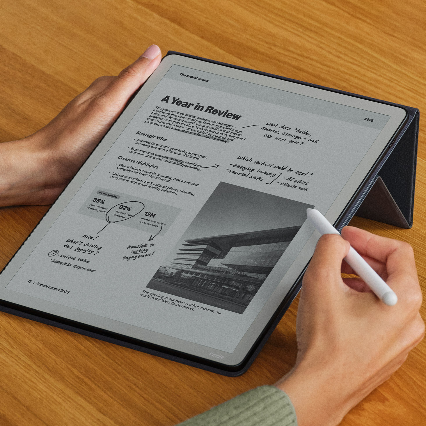 Person using a Kindle Scribe to annotate a business report titled "A Year in Review" with a stylus. The e-reader displays strategic wins, creative highlights, and performance metrics for 2025.